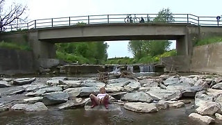 Blonde pissing outside in a river